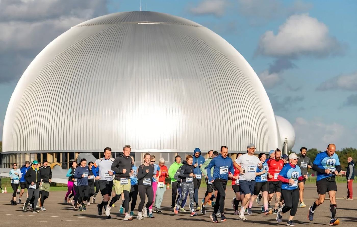 Läuferinnen und Läufer beim Start vor der silbernen Luftschiffhalle